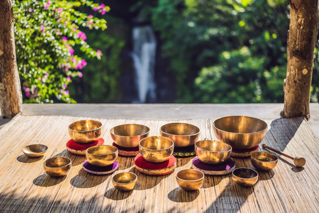 tibetan,singing,bowls,on,a,straw,mat,against,a,waterfall