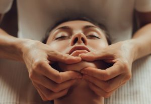 hands,of,female,chiropractor,massaging,face,of,young,woman,lying