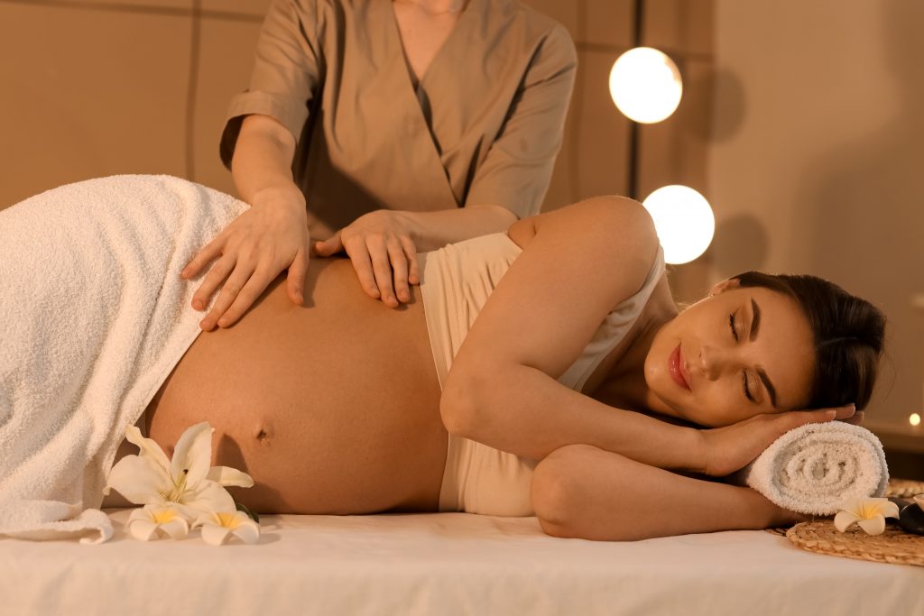 young,pregnant,woman,having,massage,in,dark,spa,salon